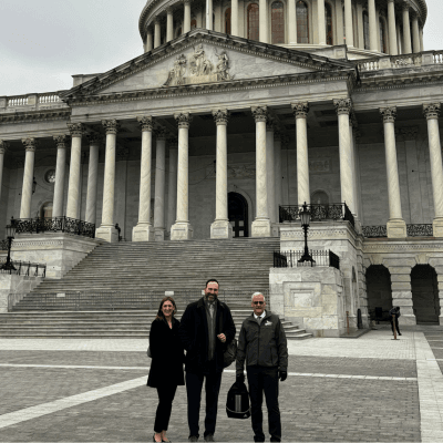 Jennifer Lindsay, Steve Stuart, and Rob Aichele stand in front of the U.S. Capitol building.