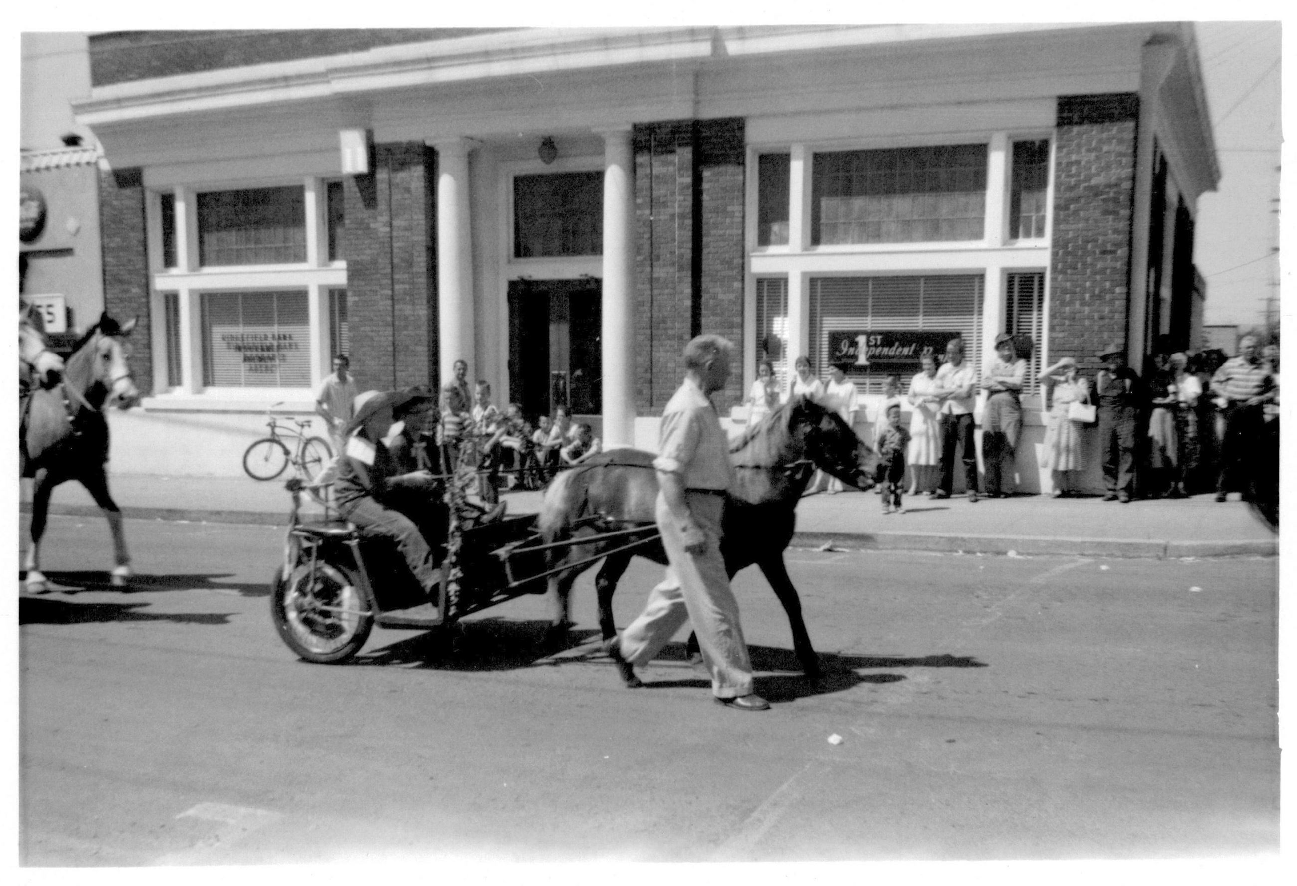 Parade float passes in front of bank building during parade, 1959.