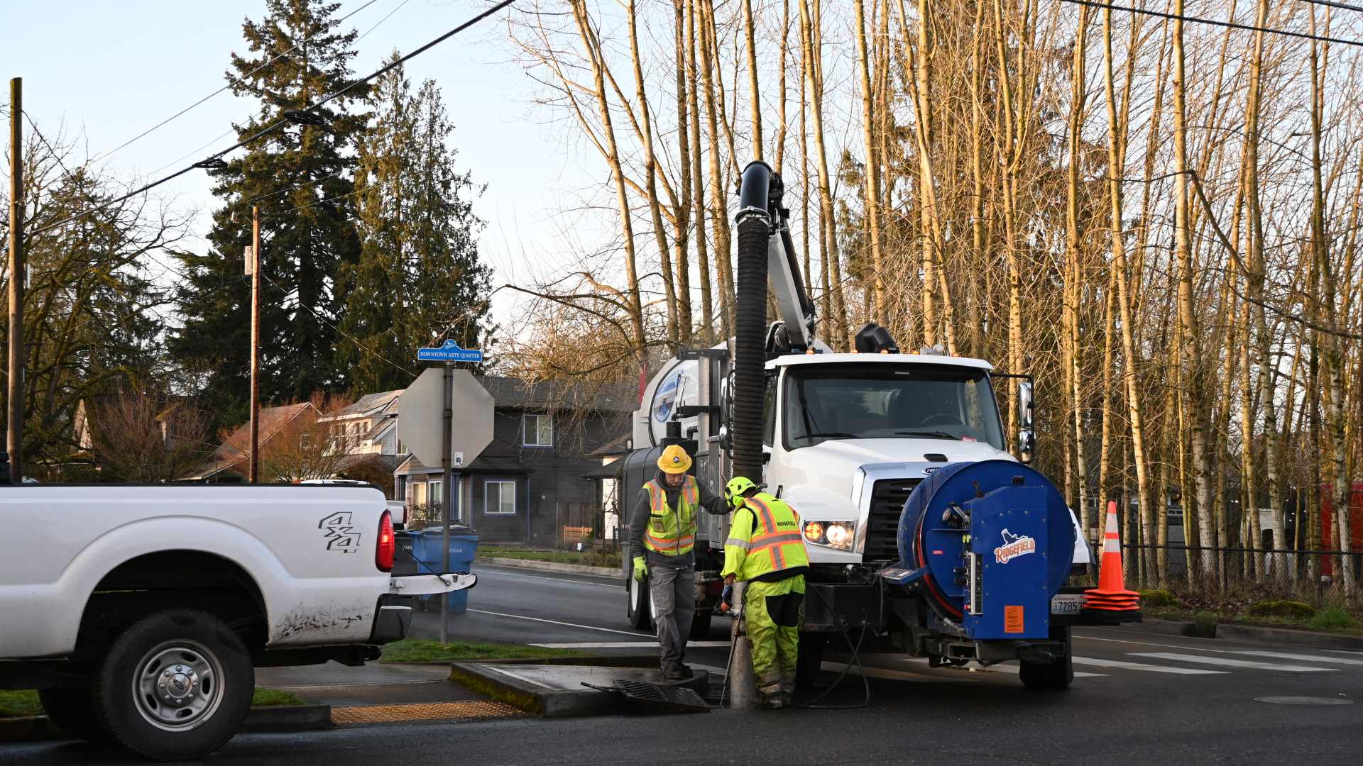 Two public works employees using the vactor truck to perform maintenance.