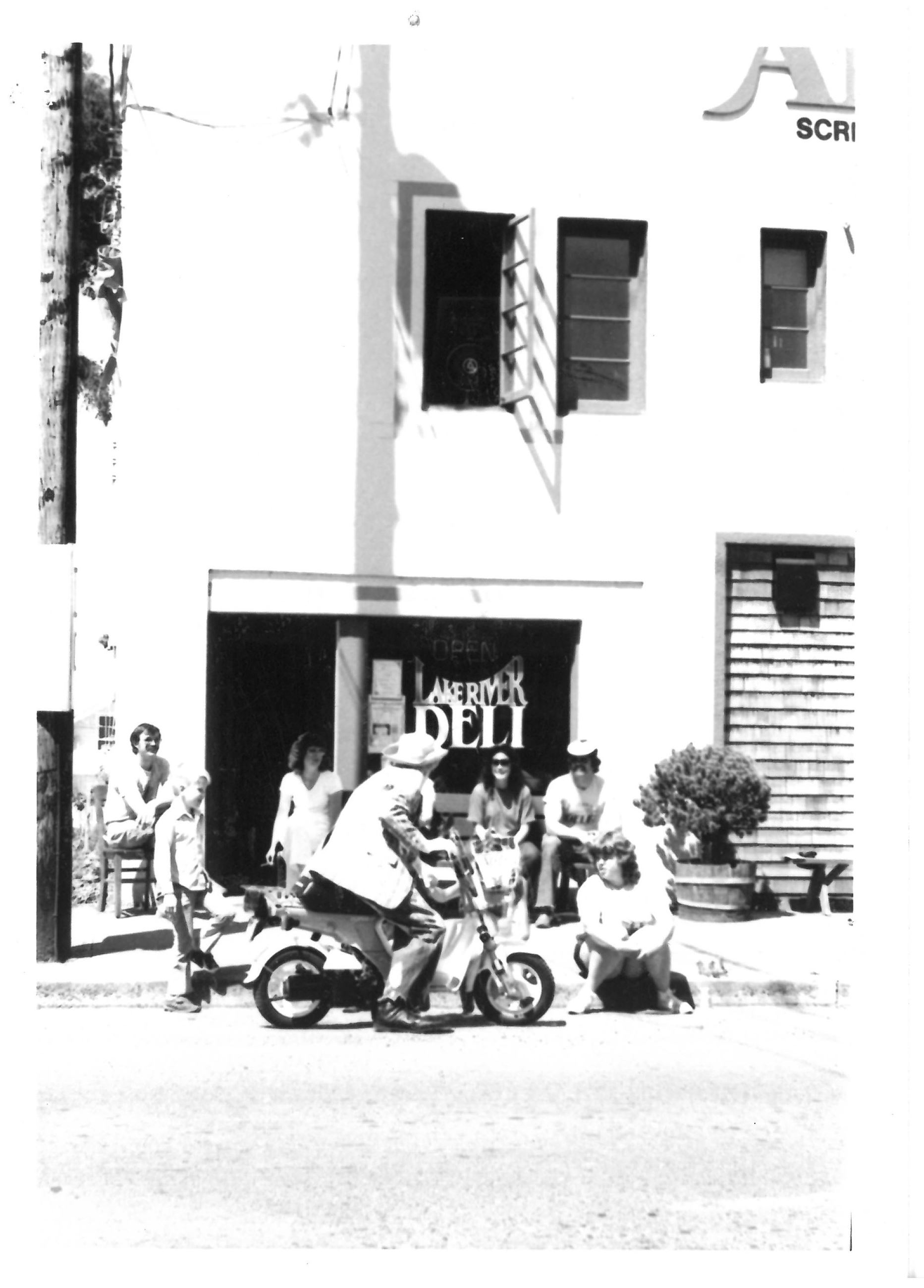 Man on a street bike talks to bystanders in front of what is now Old Liberty Theater.