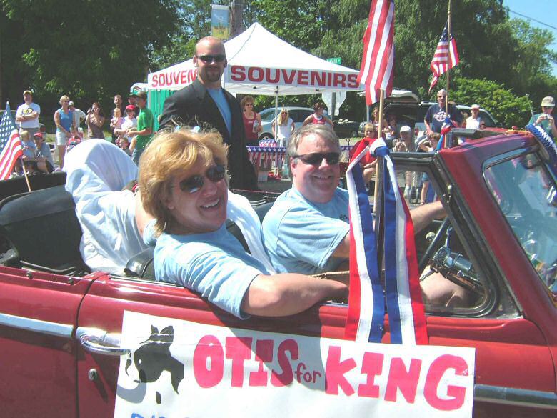 A car with sign 'Otis for King' on the side driven in 4th of July parade by Cathy and Scott Hu